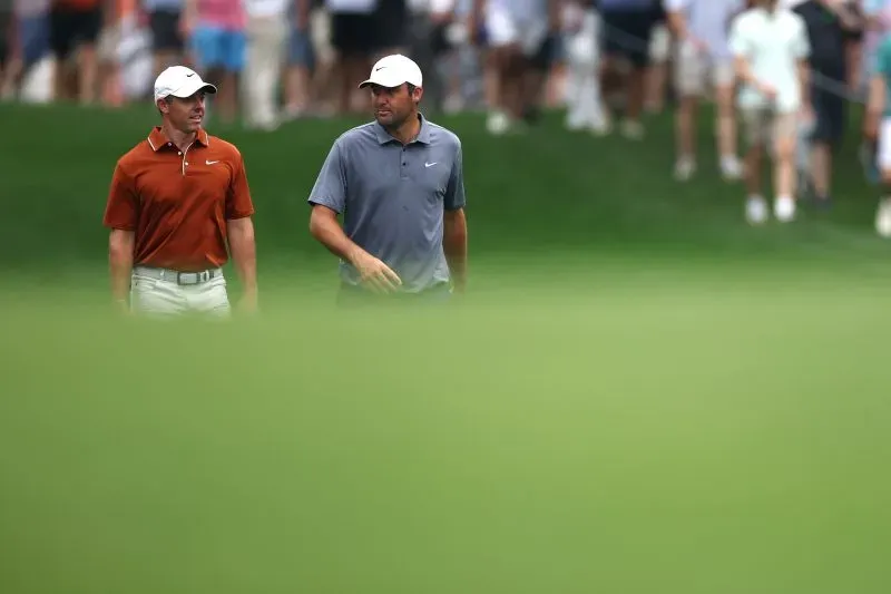 لاعبا جولف يسيران على الملعب خلال بطولة رابطة محترفي الجولف للمحترفين 2025 في شارلوت، مع حشد من المشجعين في الخلفية.