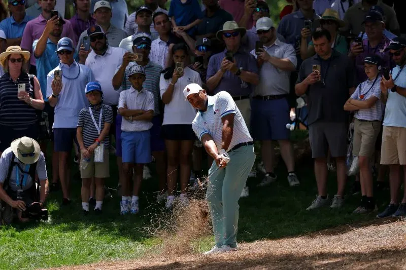 سكوتي شيفلر في جولة الجولف، يضرب الكرة من الرمال وسط حشد من المشجعين، مع أجواء مشمسة في نادي كويل هولو بولاية نورث كارولينا.