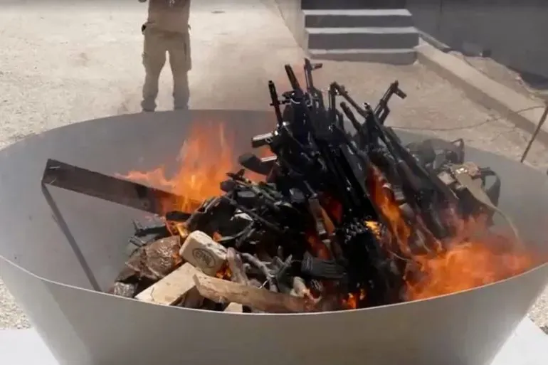 نيران مشتعلة في وعاء كبير تحرق أسلحة، تعبير عن نزع السلاح من قبل حزب العمال الكردستاني كخطوة نحو السلام في تركيا.