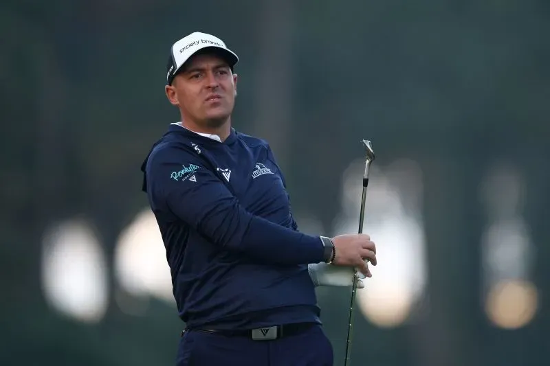 لاعب غولف أمريكي يظهر وهو يستعد لضرب الكرة، مع خلفية غابية، خلال بطولة الجولف في TPC Sawgrass.