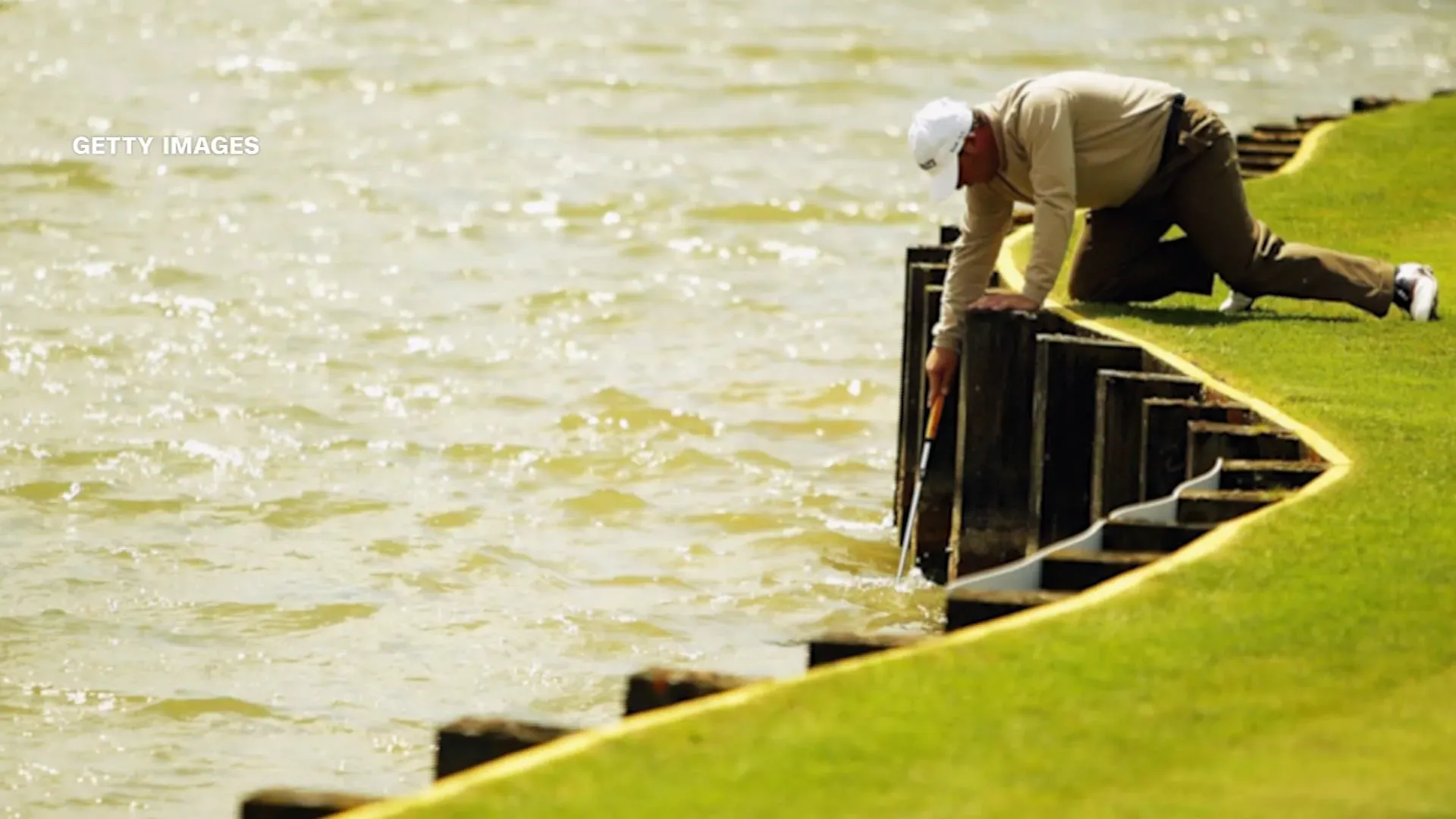 لاعب غولف يستعيد كرة من الماء بجانب الحفرة 17 في بطولة اللاعبين، مع مشهد البحيرة والأخشاب المحيطة.