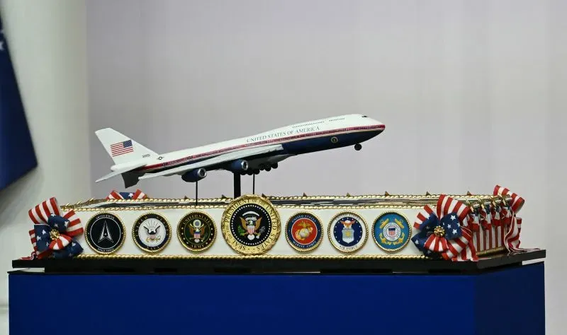 نموذج مصغر لطائرة Air Force One فوق قاعدة تحمل شعارات القوات المسلحة الأمريكية، يرمز إلى أهمية الطائرة في النقل الرئاسي.