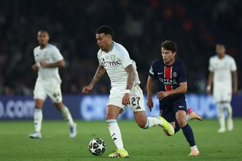 لاعب أستون فيلا مورجان روجرز يركض بالكرة خلال مباراة دوري أبطال أوروبا ضد باريس سان جيرمان، مع وجود لاعب من الفريق المنافس خلفه.