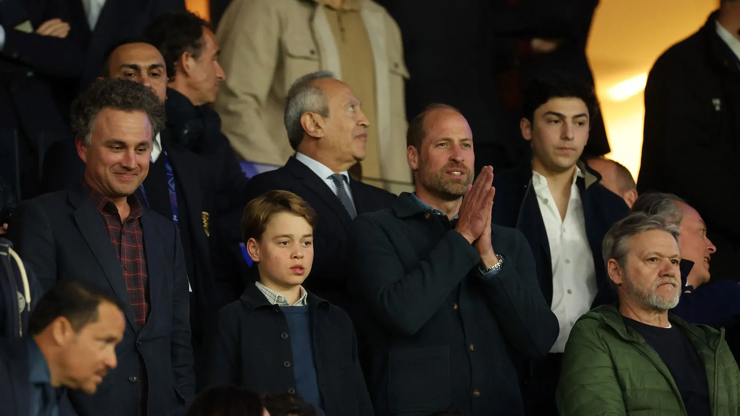 الأمير ويليام وابنه جورج يشاهدان مباراة أستون فيلا ضد باريس سان جيرمان في مدرجات ملعب بارك دي برانس، مع أجواء حماسية.