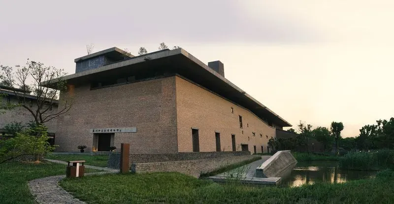 مبنى حديث بتصميم بسيط من الطوب، محاط بمساحات خضراء ومياه، يمثل رؤية ليو جياكون المعمارية التي تركز على التكامل مع الطبيعة.