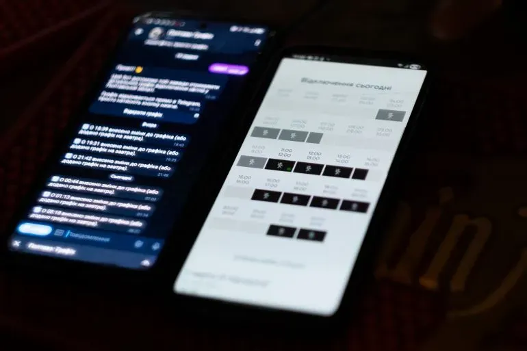 شاشتان هاتفيتان تظهران معلومات حول انقطاع الكهرباء في أوكرانيا، مع رسائل وتوقيتات توضح حالة الطاقة الحالية.