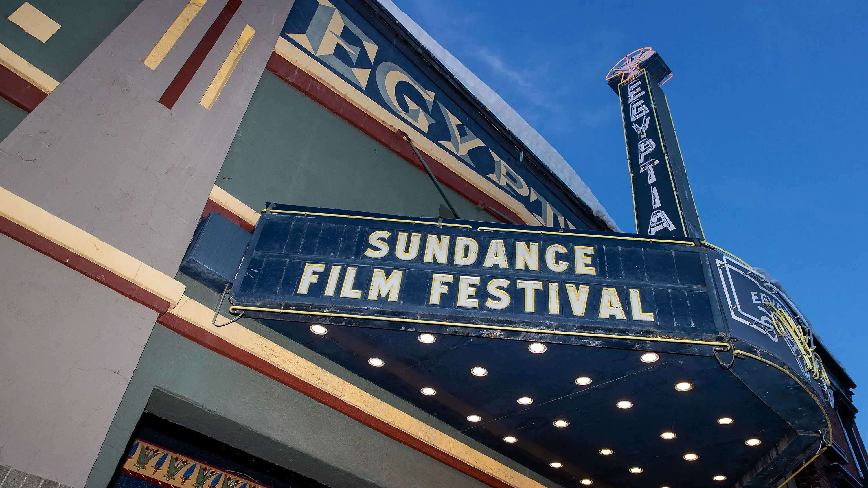 شعار مهرجان صندانس السينمائي على لافتة أمام دار سينما، مع سماء زرقاء في الخلفية، يمثل الانتقال المرتقب للمهرجان إلى بولدر، كولورادو.