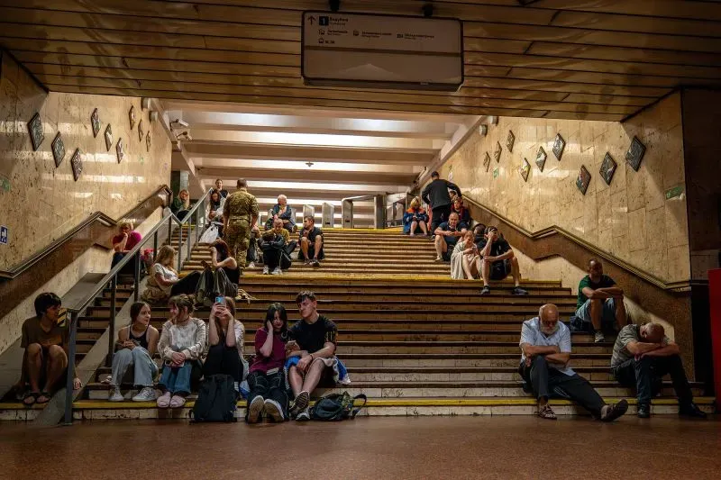 مشهد لمجموعة من الأشخاص في محطة مترو في كييف، حيث يجلس البعض على الدرج بينما يتحدث آخرون، في ظل تصاعد الهجمات الجوية الروسية.