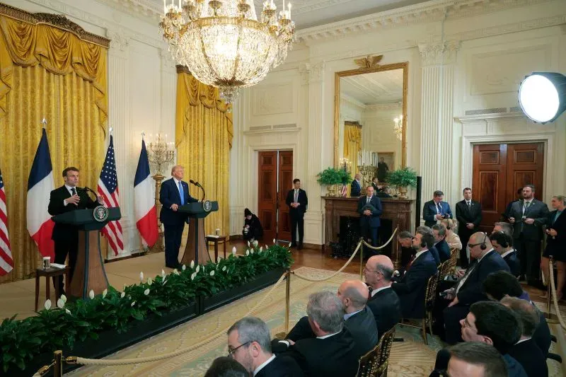 مؤتمر صحفي مشترك في البيت الأبيض، حيث يتحدث ترامب مع الرئيس الفرنسي ماكرون، مع وجود صحفيين ومراسلين في الخلفية.