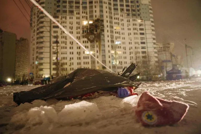 صورة تظهر شخصًا مغطى في الثلوج بعد هجوم روسي على مدينة أوكرانية، مع خلفية لمبنى سكني مضاء في الليل.