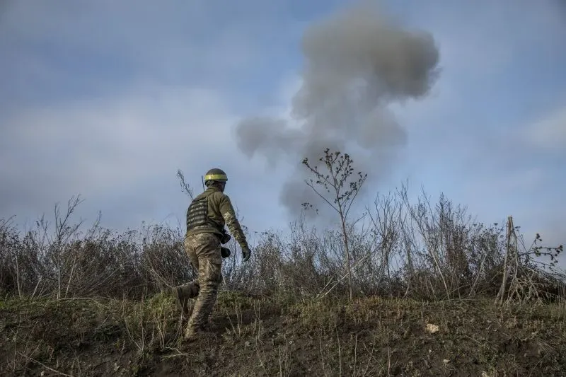 جندي يرتدي خوذة يسير نحو سحابة من الدخان في منطقة ملغومة، مما يعكس التوترات العسكرية المتزايدة في أوروبا.