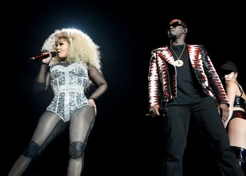 مغنية تؤدي على المسرح بجانب ديدي، مع إضاءة خلفية مبهرة، تعكس لحظة تفاعل قوي بينهما خلال عرض موسيقي.