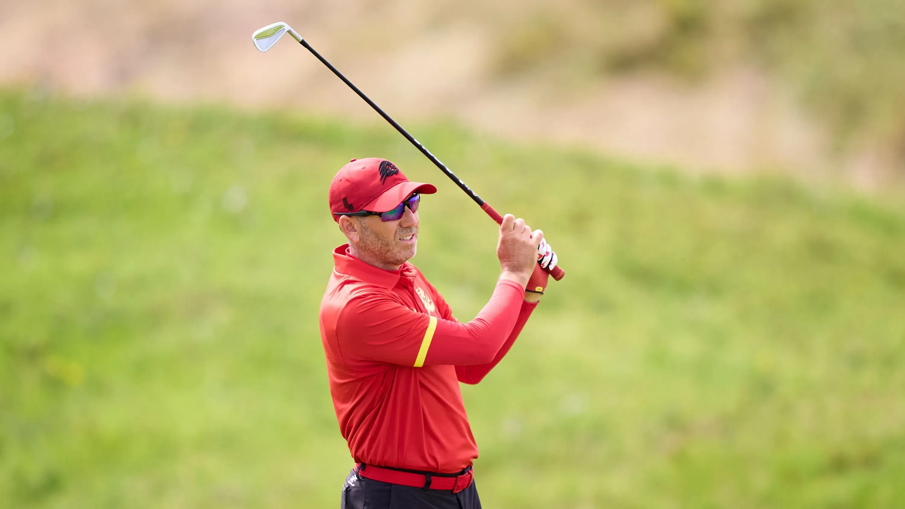 سيرجيو غارسيا، لاعب الجولف الإسباني، يستعد لضربة في ملعب الجولف، مرتديًا قميصًا أحمر وقبعة، مع تركيز واضح على وجهه.