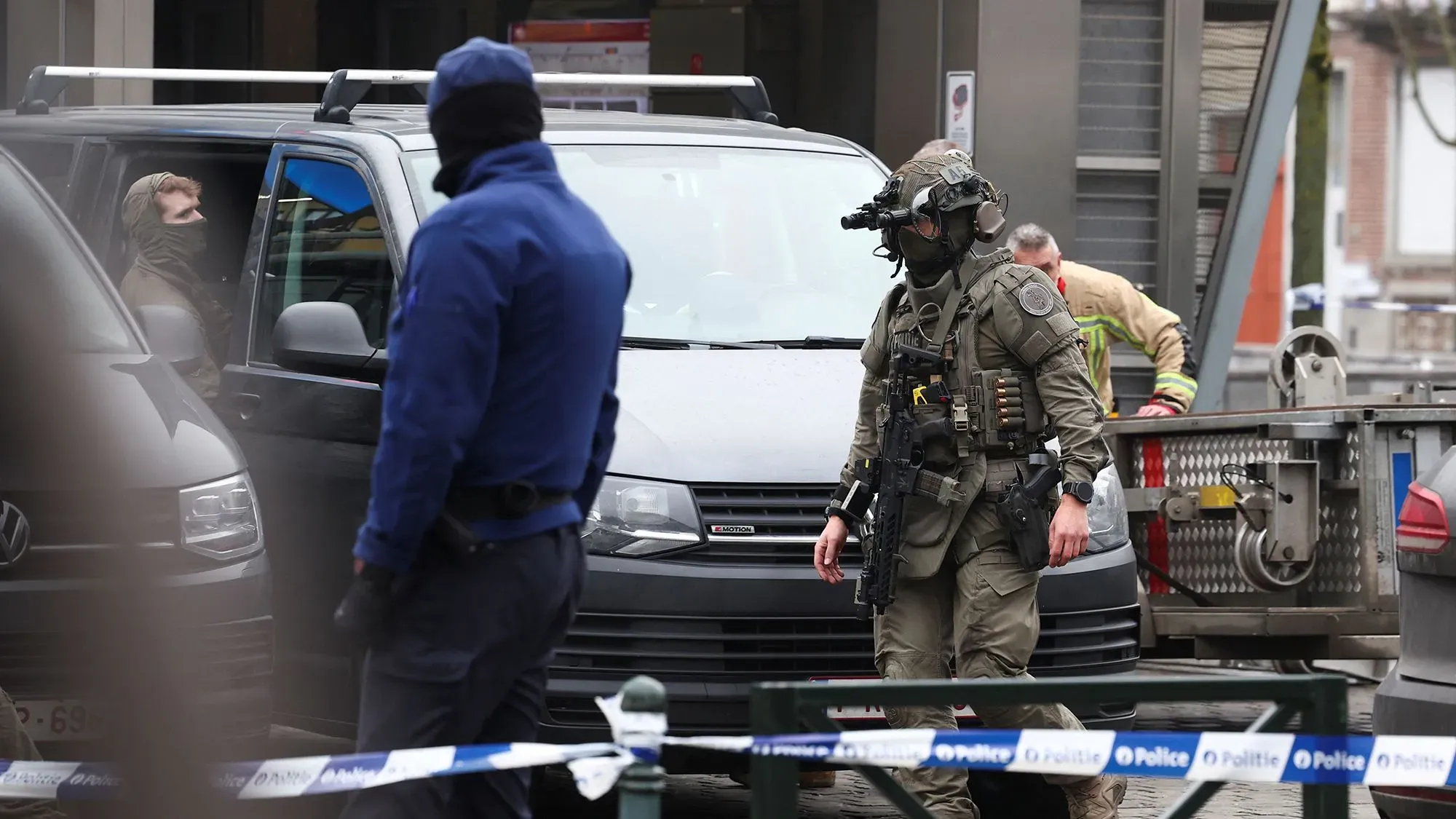 وجود شرطي مسلح يرتدي زيًا عسكريًا في موقع حادث إطلاق نار بمحطة مترو كليمنصو في بروكسل، مع وجود سيارات الشرطة في الخلفية.