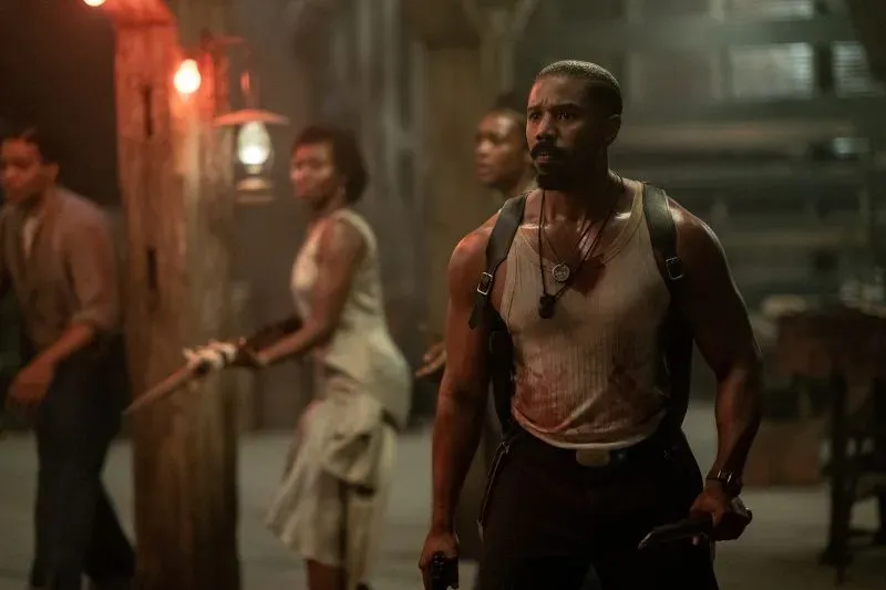 مشهد من فيلم "المذنبون" يظهر مجموعة من الشخصيات في بيئة مظلمة، حيث يرتدي البطل ملابس مدمرة ويبدو في حالة تأهب.