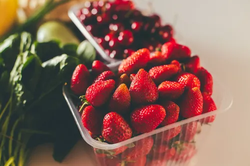 تظهر الصورة مجموعة من الفراولة الطازجة والخضروات الورقية، مما يعكس نتائج تقرير مجموعة العمل البيئي حول بقايا المبيدات الحشرية.