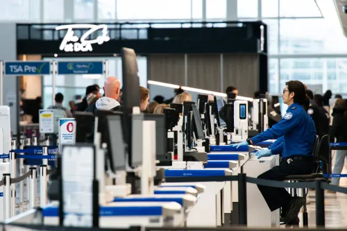 طوابير طويلة في مطار مزدحم، حيث يعمل موظف أمن في إدارة أمن النقل وسط نقص في الموظفين بسبب الإغلاق الجزئي للحكومة.