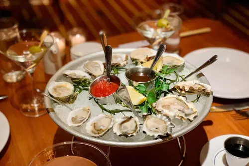 طبق من المحار الطازج يقدم مع صلصات متنوعة، على الثلج، في مطعم، وسط أجواء عصرية، مما يبرز مخاطر تناول المحار الملوث بالسالمونيلا.