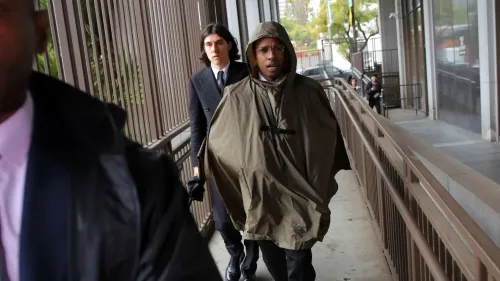 A$AP Rocky يتجول في المحكمة مرتديًا معطفًا واقيًا، برفقة شخص آخر، وسط أجواء من التوتر خلال محاكمته بتهمة الاعتداء.