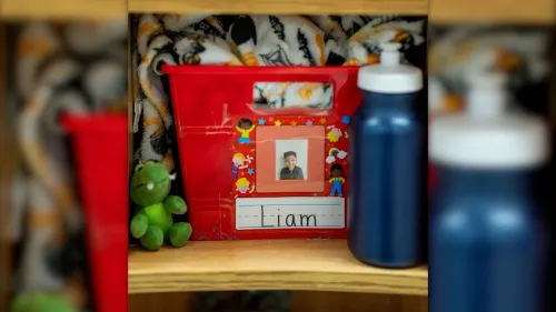 صورة لصندوق أحمر يحمل صورة طفل يدعى ليام، مع زجاجتين مياه ولعبة دمية، تعكس قلق العائلات في مينيابوليس بسبب عمليات الهجرة.