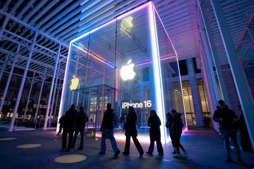 واجهة متجر Apple تعرض إعلانًا لجهاز iPhone 16، مع إضاءة ملونة وجمهور ينتظر الدخول، مما يعكس اهتمامًا كبيرًا بالمنتجات الجديدة.