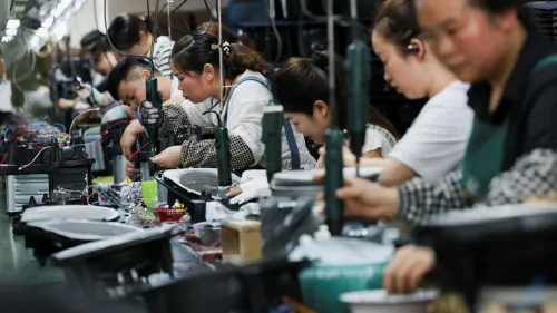 عمال في مصنع صيني يقومون بتجميع المنتجات الإلكترونية، مما يعكس زيادة الصادرات الصينية في ظل التوترات التجارية العالمية.