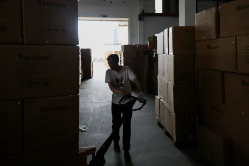 عامل يقوم بتنظيف مستودع مليء بالصناديق، في سياق ارتفاع صادرات الصين وتحديات التجارة العالمية.