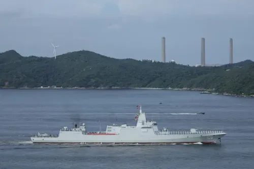 سفينة حربية صينية تبحر في المياه المحيطة بتايوان، مع ظهور التلال والمرافق الصناعية في الخلفية، في إطار تدريبات عسكرية.