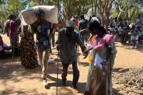 مشهد من منطقة تيغراي يظهر أشخاصًا يتلقون المساعدات الإنسانية، مع التركيز على رجل مسن يتلقى الدعم من شاب، في ظل ظروف صعبة.