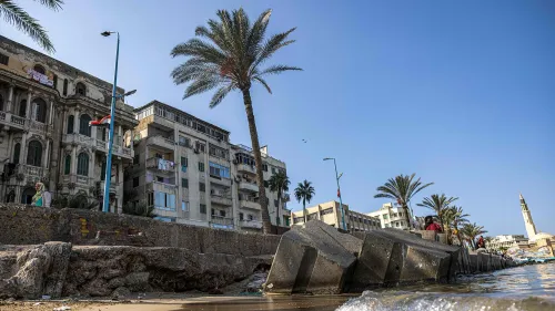 انهيار جزء من الرصيف في الإسكندرية، مع ظهور مبانٍ قديمة وحديثة، مما يعكس تأثير ارتفاع منسوب مياه البحر على المدينة.