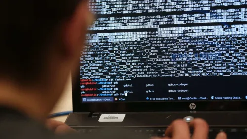 شخص يعمل على كمبيوتر محمول يعرض شاشة مليئة بالشيفرات البرمجية، مما يشير إلى نشاطات القرصنة الإلكترونية المرتبطة بمجموعة "العنكبوت المبعثر".