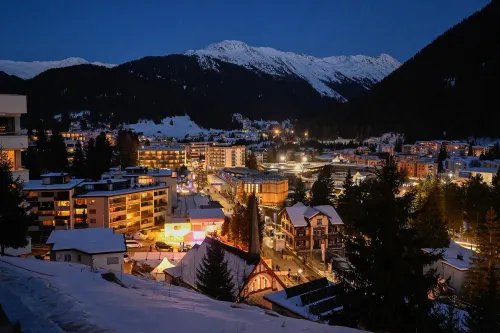 منظر ليلي لمدينة دافوس السويسرية، مع إضاءة المباني المحيطة والجبال المغطاة بالثلوج في الخلفية، يرمز إلى منتدى دافوس الاقتصادي.