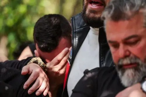 رجال يعبرون عن حزنهم خلال مراسم تأبين، مع تعابير وجهية تعكس الألم والفقد، في سياق تصاعد العنف في لبنان.