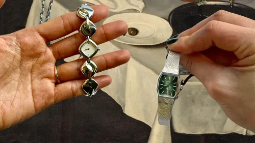 ساعتان عتيقتان تُعرضان في يدين، واحدة بقرص فضي والأخرى بقرص أخضر، مع خلفية فنية تُبرز اهتمام الجيل Z بالتصميم الكلاسيكي.