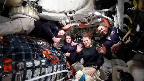 أفراد طاقم بعثة أرتميس 2 داخل كبسولة أوريون، يبتسمون ويحيون الكاميرا، محاطين بمعدات الفضاء.