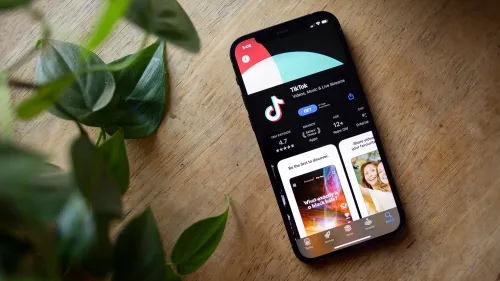 واجهة تطبيق تيك توك على هاتف ذكي، مع ظهور شعار التطبيق ومعلومات تقييمه، محاطة بأوراق نباتية، تعكس التوتر حول حظره في الولايات المتحدة.