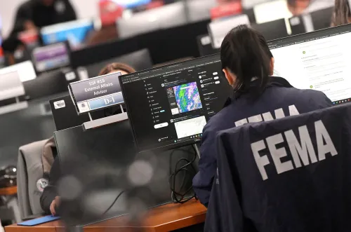 موظفة في FEMA تعمل على جهاز كمبيوتر في مركز إدارة الطوارئ، مع وجود شاشات تعرض معلومات الطقس. الصورة تعكس تأثير الإغلاق الحكومي على العاملين في الوزارة.
