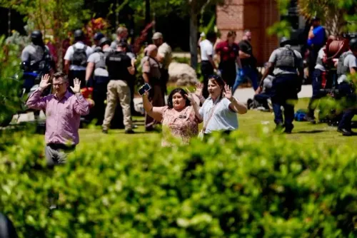 طلاب وموظفون في جامعة ولاية فلوريدا يرفعون أيديهم أثناء استجابة الشرطة لحادث إطلاق نار، مع وجود قوات الأمن في الخلفية.