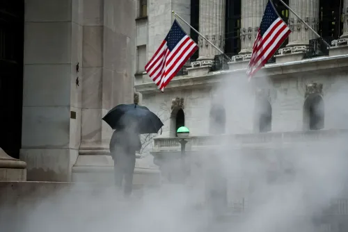 رجل يحمل مظلة سوداء يسير في ضباب كثيف أمام مبنى يحتوي على أعلام أمريكية، مما يعكس أجواء القلق في الأسواق المالية.