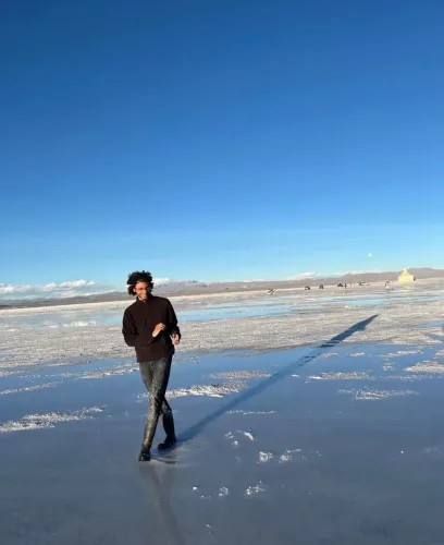 شاب يسير على سطح مائي في منطقة صحراوية، مع سماء زرقاء صافية في الخلفية، يعكس روح المغامرة والحرية بعد تجربة احتجاز صعبة في فنزويلا.