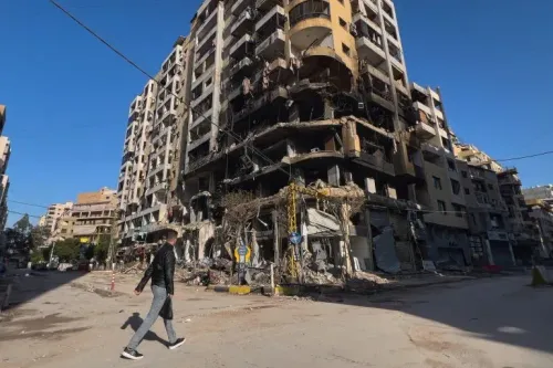مبنى سكني مدمر في بشامون، بيروت، يظهر آثار الغارة الإسرائيلية، مع وجود حطام في الشارع وشخص يمشي بجوار المبنى.