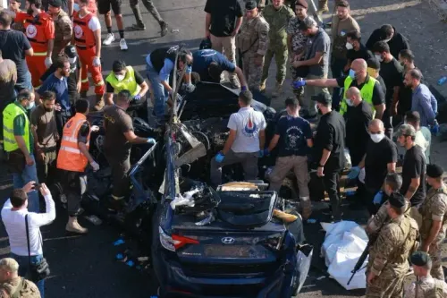 موقع الحادث في بلدة شقرا بعد غارة إسرائيلية، حيث يتجمع رجال الإنقاذ والجنود حول سيارة مدمرة، مع وجود مصابين في الموقع.