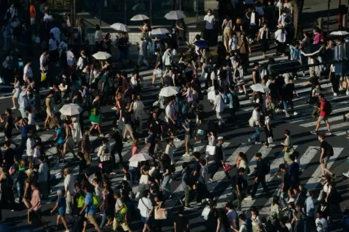 حشود من الناس في مدينة يابانية يعبرون الشارع، يحملون مظلات لحماية أنفسهم من الحرارة الشديدة التي تجاوزت 41 درجة مئوية.