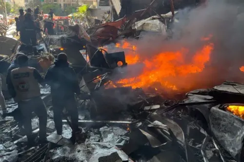 دخان يتصاعد من حطام مبنى بعد هجوم إسرائيلي في لبنان، حيث يتجمع رجال الإنقاذ وسط الفوضى. الهجوم أسفر عن مقتل وإصابة العشرات.