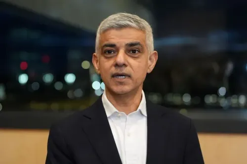 صادق خان، عمدة لندن، يتحدث في مؤتمر مع خلفية مضاءة، مع التركيز على قضايا الهجرة وتأثير ترامب على الأمريكيين الراغبين في الحصول على الجنسية البريطانية.