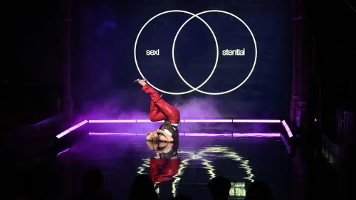 روبن تؤدي أغنيتها "Sexistential" على المسرح، مرتدية سروالًا جلديًا أحمر وقميصًا أبيض، مع تصميمات جريئة تعكس أسلوبها الفريد.