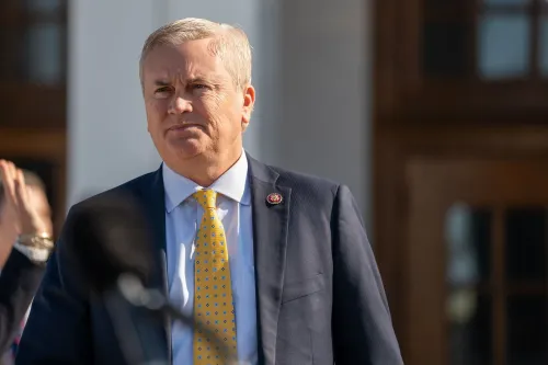 رجل يرتدي بدلة رسمية مع ربطة عنق صفراء، يبدو جادًا وهو يتحدث في حدث رسمي، في سياق فضيحة الاحتيال في الرعاية الاجتماعية بمينيسوتا.