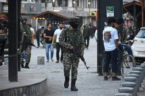 جنود يرتدون زيًا عسكريًا ويحملون أسلحة في منطقة حضرية، بينما يتجول مدنيون في الخلفية، مما يعكس التوترات الأمنية بين الهند وباكستان.