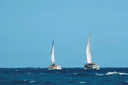 زورقان شراعيان مكسيكيان يبحران في البحر الكاريبي، جزء من قافلة مساعدات إنسانية إلى كوبا، تحت سماء زرقاء.