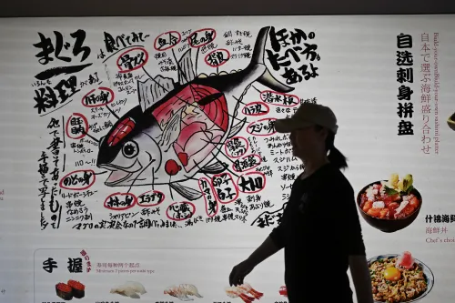 رسم توضيحي يوضح أجزاء سمكة مع تسميات باللغة اليابانية، بينما تسير امرأة أمامه في مطعم ياباني.